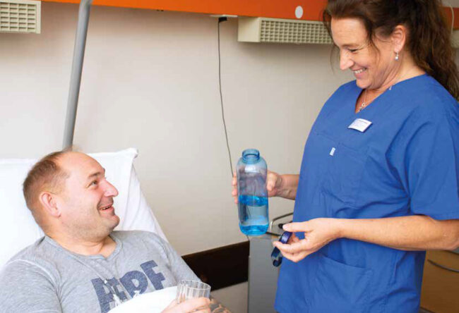 Titelbild des Gesundheitsmagazins "Ihre Sprechzeit" 2024-1: Eine Pflegekraft reicht einem Patienten Wasser.