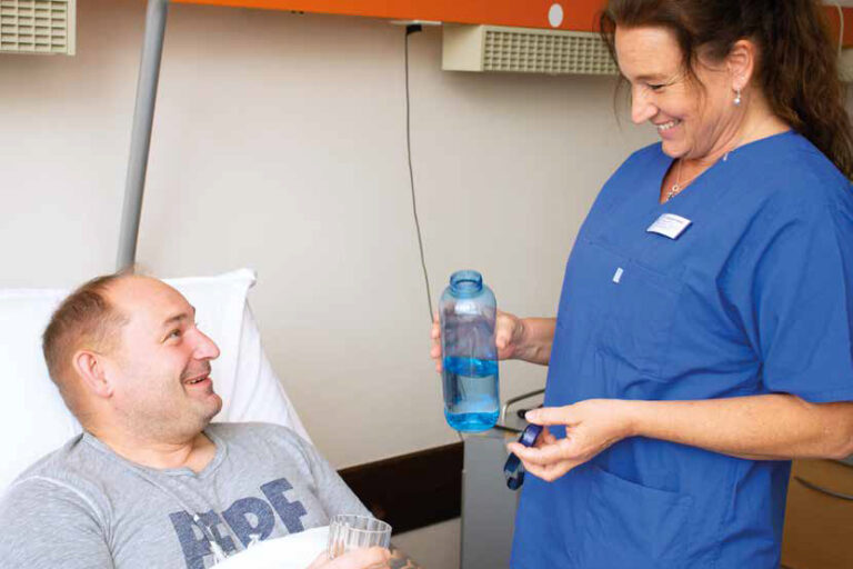 Titelbild des Gesundheitsmagazins "Ihre Sprechzeit" 2024-1: Eine Pflegekraft reicht einem Patienten Wasser.